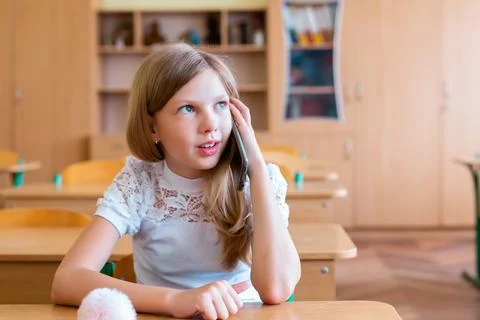 Student studies at a desk in a classroom using a smartphone during school hou Stock Photos