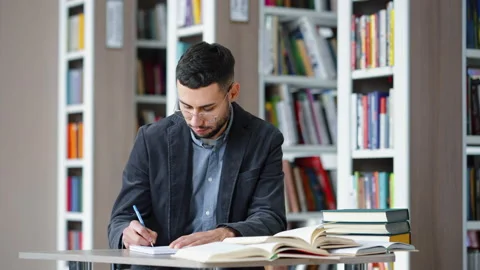 Student studying in library and smiling at camera Stock Footage 202062117