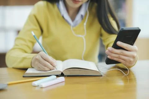 Student studying at library using phone. Foto stock