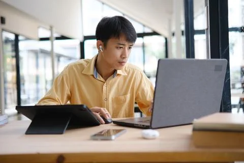 Student studying online and preparing for exams with digital devices and book Stockfoto's