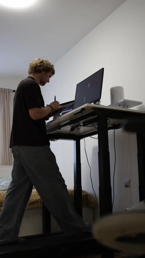 Student takes notes while walking on treadmill and learning video editing at com Stockbeeldmateriaal 346880600