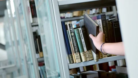 Student taking a book from a library shelf Stock Footage 249272523