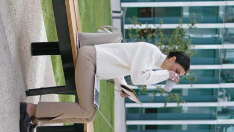 Student taking coffee break from online studying sitting bench vertical oriented Stock Footage 263932924