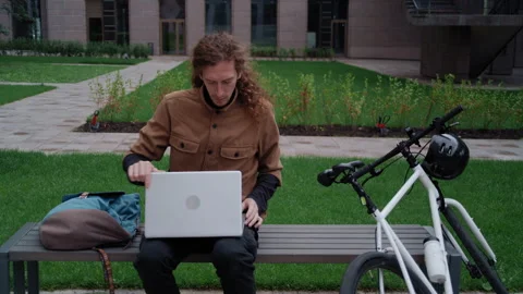 Student taking laptop from backpack and working on bench 库存影片 317561604