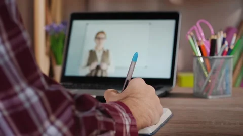 Student taking notes during online educational lesson on laptop from home. Stock Footage 334800860