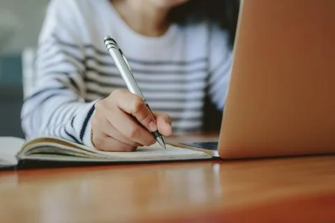Student taking notes with laptop on table Fotos de archivo