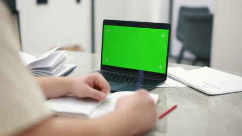 Student taking notes using a laptop with green screen Stock Footage 340925762