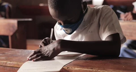 Student taking notes while wearing face mask due to the coronavirus emergency Stock Footage 146489780