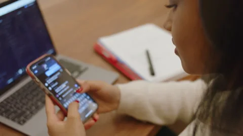 Student texting on smartphone while studying at a desk in a classroom Stock Footage 312769745