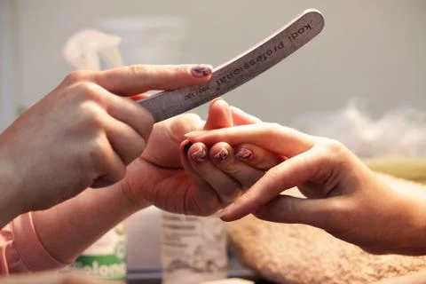 A student at the training courses of a manicure prepares the hand of a lady c Stock Photos