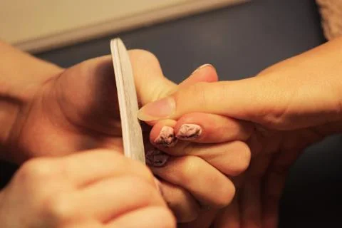 A student at the training courses of a manicure prepares the hand of a lady c Stock Photos