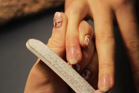 A student at the training courses of a manicure prepares the hand of a lady c Stock Photos