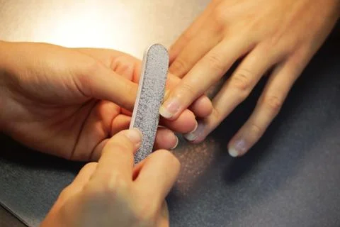 A student at the training courses of a manicure prepares the hand of a lady c Stock Photos