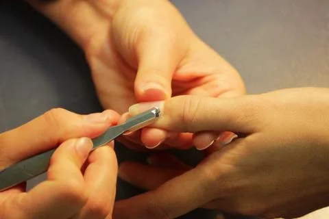 A student at the training courses of a manicure prepares the hand of a lady c Stock Photos