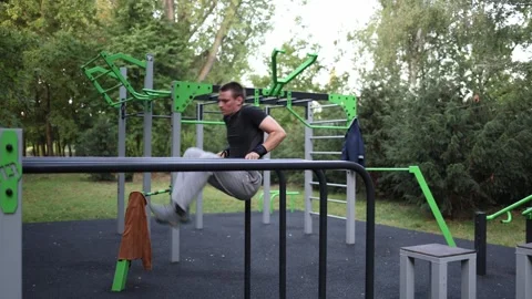 Student trains on parallel bars in outdoor gym holding strong L sit position wit Stock-Footage 316701472