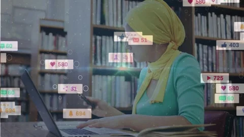 Student typing on laptop in library, social icons appearing and drawing focus to Stock Footage 330161787