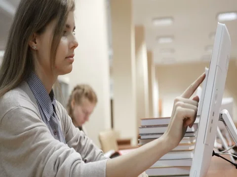 Student typing on touch screen computers in library, searching through database Stock Footage 82201586