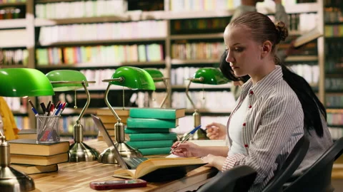 Student in university library distracted by smartphone notification Stock Footage 336360563