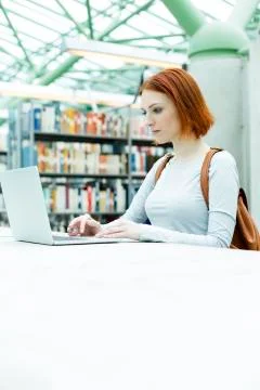 Student in a university library using laptop Stock Photos