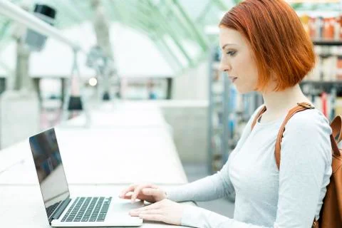 Student in a university library using laptop Stock Photos