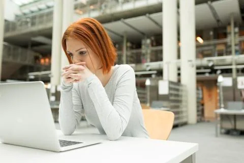Student in a university library using laptop 写真素材
