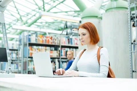 Student in a university library using laptop Stock Photos
