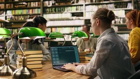 Student uses laptop with AI chatbot interface at library table Stock Footage 336359576