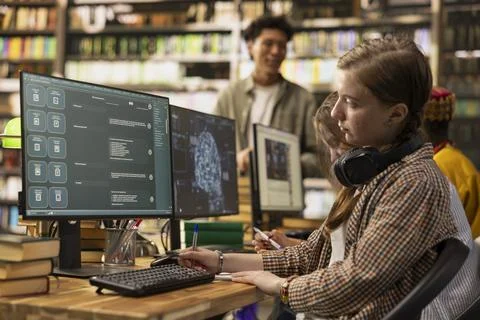 Student uses virtual assistant and typing on keyboard beside other screen Foto stock