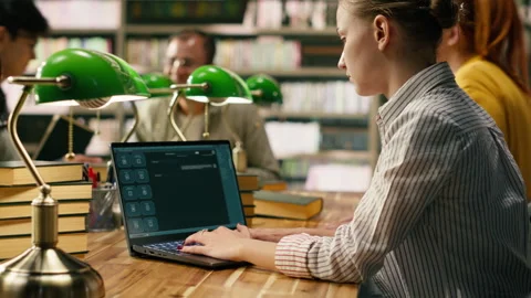 Student using AI study assistant interface typing on laptop at library table Stock Footage 336361770