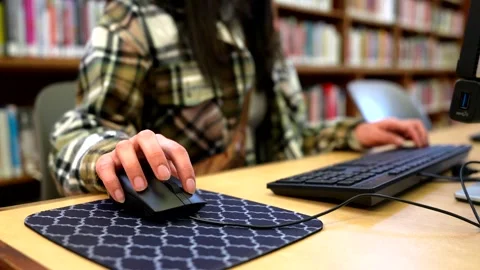 Student using computer mouse and keyboard in library Stock Footage 333105679