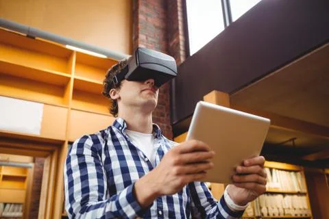 Student using digital tablet and virtual reality headset in library Foto stock