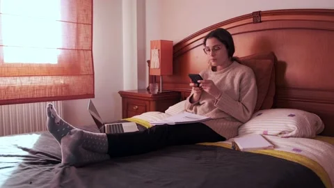 Student using her mobile phone on bed. Stock Footage 145811389
