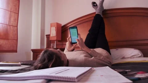 Student using her phone while lying on bed. Stock Footage 145811406