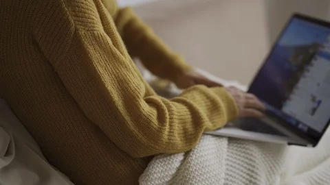 Student using laptop at home lying on sofa under blanket using computer serching Видео 119524359