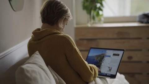Student using laptop at home lying on sofa under blanket using computer serching Vidéo 119524446