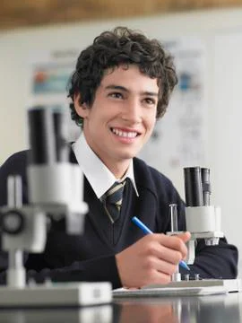Student Using Microscope And Taking Notes 写真素材