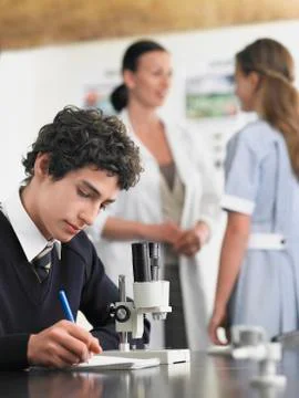 Student Using Microscope And Taking Notes In Laboratory Stock Photos