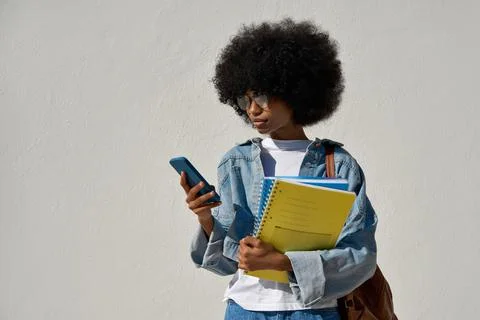 A student using phone in her hand and looking at her phone on yellow background Stock Photos