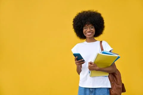 A student using phone in her hand and looking at her phone on yellow background Stock Photos