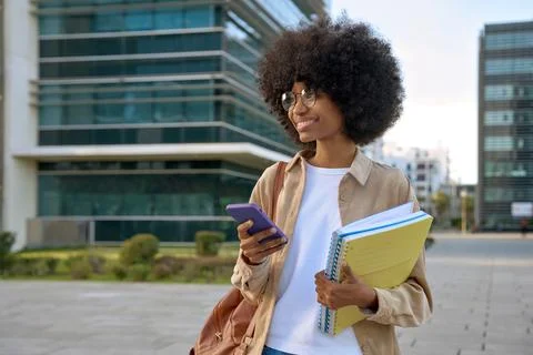 A student using phone in her hand and looking aside on city background Stock Photos