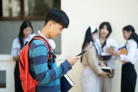 Student using smartphone with friends in background Stock Photos