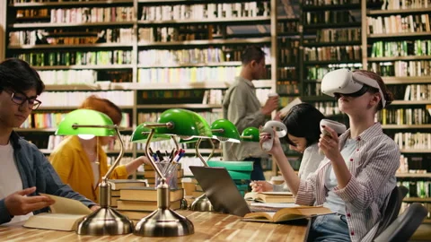Student using virtual reality headset and hand controllers at library desk Stock Footage 336358602