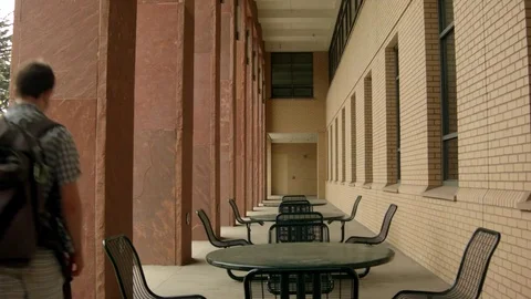 Student walking down Outdoor Corridor Stock Footage 77256130