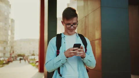 Student walking with smartphone. Portrait view of young man in casual jeans Stock Footage 141557466
