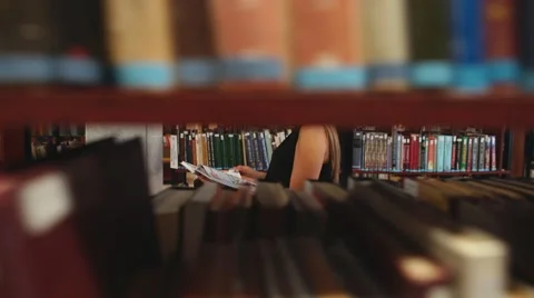 Student walking through the library and reading a book Stock Footage 68137750
