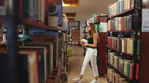 Student walking through the library and reads the encyclopedia Stock Footage 68140592