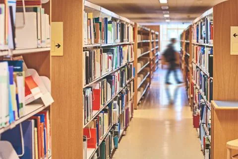 Student walking through a passage between the bookcases in the library Stock Photos