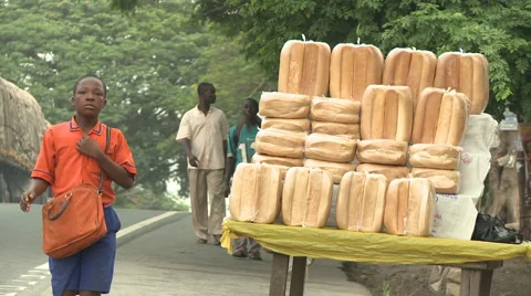 STUDENT WALKS PAST A ROADSIDE BREAD STAND Stock Footage 60633454