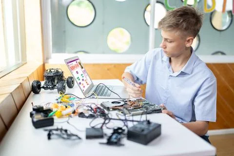 Student watch code on laptop and use screwdriver fix motherboard. Edification. Stock Photos