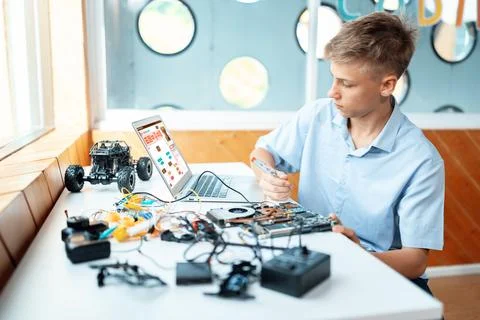 Student watch code on laptop and use screwdriver fix motherboard. Edification. Stock Photos